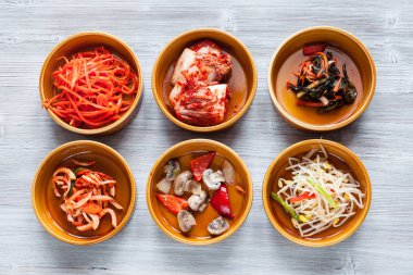 Kore mutfağı - çeşitli yan yemekler (Banchan veya Panchan) seramik kase üstten görünüm gri masada