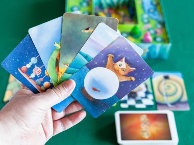 player holds picture cards in Dixit board game clipart