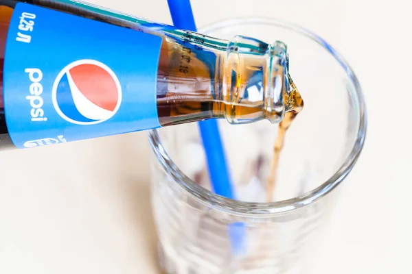Pepsi bebida flui do pescoço da garrafa para o vidro — Fotografia de Stock