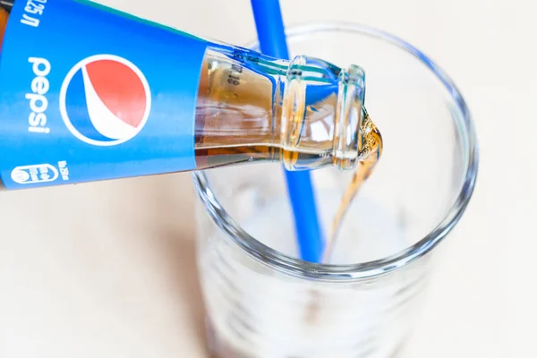 Einschenken des Pepsi-Getränks aus der Flasche ins Glas — Stockfoto