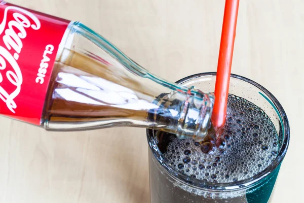 Versando la bevanda Coca-Cola dalla bottiglia nel bicchiere — Foto Stock
