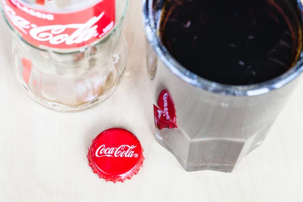 Tampa da coroa perto de vidro e garrafa vazia de Coca-Cola — Fotografia de Stock