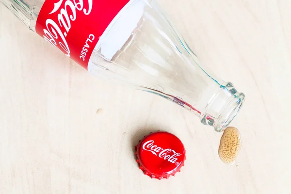 Čepice, prázdná láhev Coca-Cola a kapka nápoje — Stock fotografie