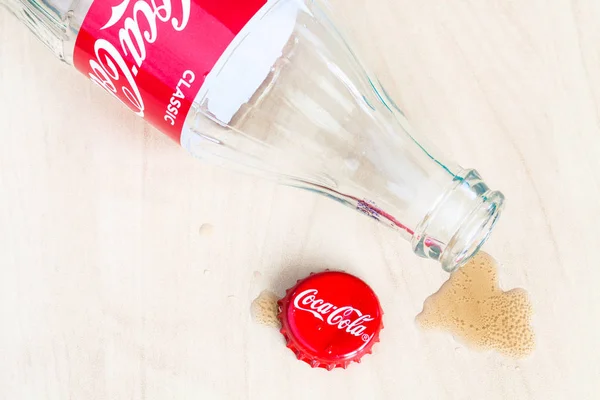 Čepice, prázdnou láhev Coca-Coly a kalužka nápoje — Stock fotografie