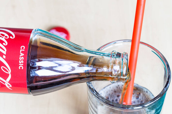 Coca-Cola beverage flows from bottle into glass