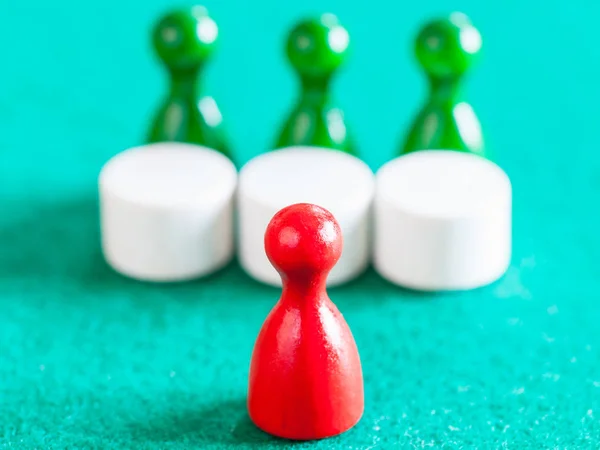Red pawn in front of three green pawns with tables — Stock Photo, Image