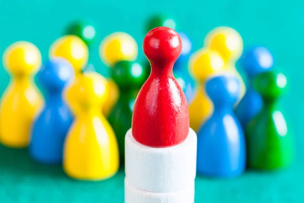 One red pawn on base over many colour pawns — Stock Photo, Image