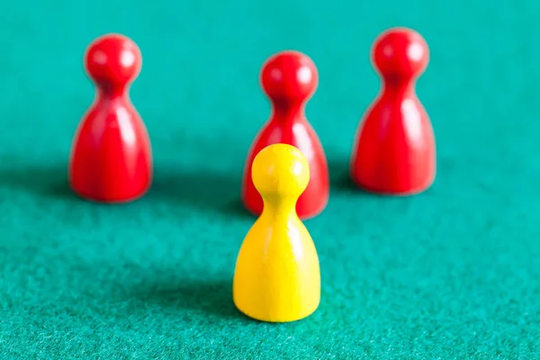 Yellow pawn in front of three red pawns on green — Stock Photo, Image