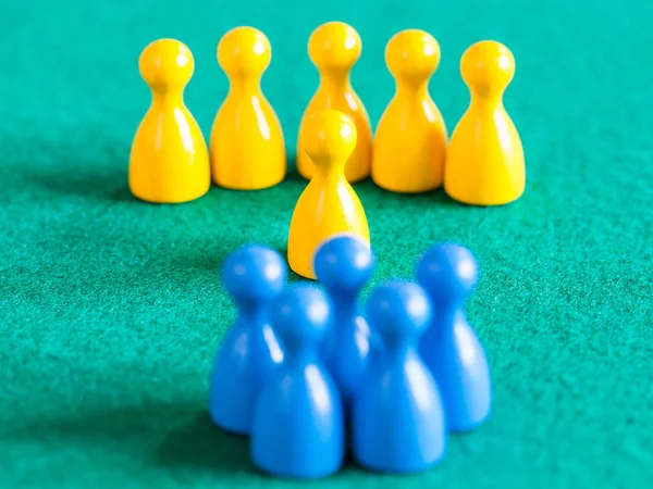 Yellow pawns with leader in front of blue pawns — Stock Photo, Image