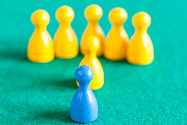 One blue pawn in front of several yellow pawns — Stock Photo, Image
