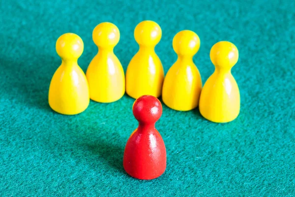 One red pawn in front of several yellow pawns — Stock Photo, Image