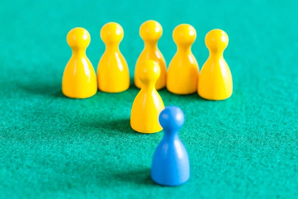 Yellow pawns with leader in front of one blue pawn — Stock Photo, Image