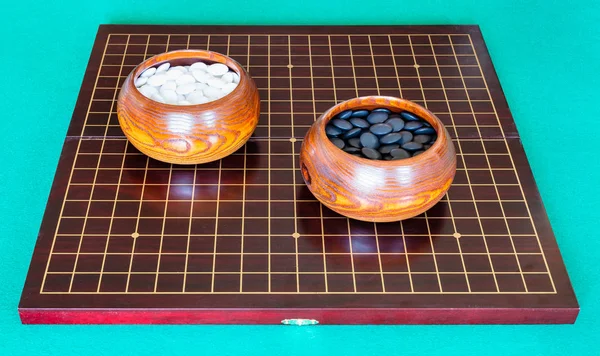 Pedras para Go jogo em tigelas no tabuleiro de madeira — Fotografia de Stock