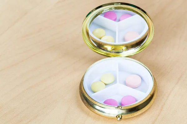 Pillbox with mirror with pink and yellow pills — Stock Photo, Image