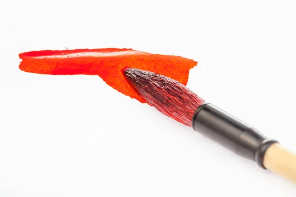 Vermelho pintado ponta de pincel em mancha de perto — Fotografia de Stock