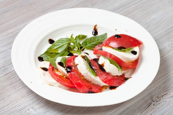 Mozzarella und Tomaten mit Basilikumblättern — Stockfoto
