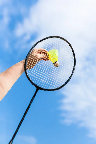 Hand slår badmintonbollen genom badminton racketen — Stockfoto