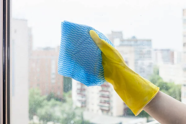 Mão limpa o vidro da janela da casa pelo pano azul — Fotografia de Stock