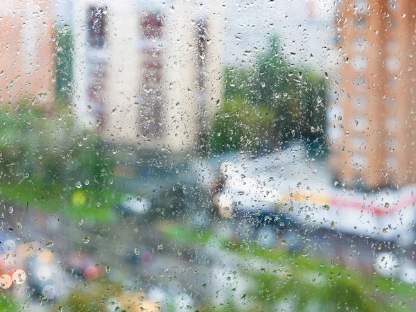 Gotas de lluvia en el vidrio de la ventana del hogar y la calle borrosa — Foto de Stock