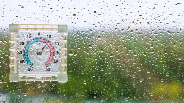 Raindrops and outdoor wet thermometer on glass — Stock Photo, Image