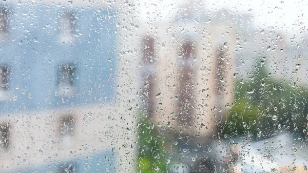 Krople deszczu na okno i niewyraźne mieszkania domy — Zdjęcie stockowe