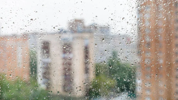 Gotas de lluvia en vidrio de ventana y paisaje urbano borroso — Foto de Stock