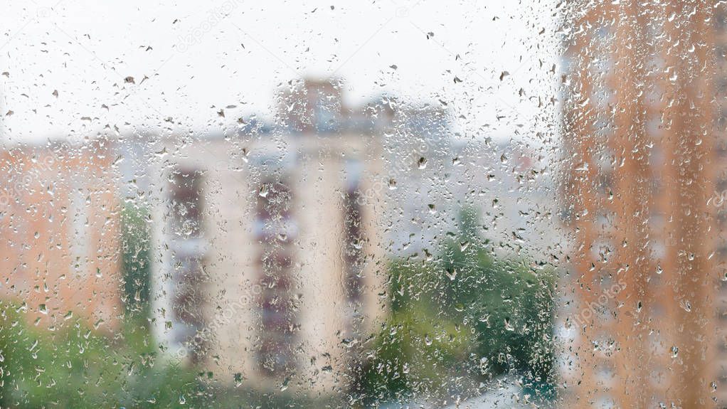 rain drops on window glass and blurred cityscape