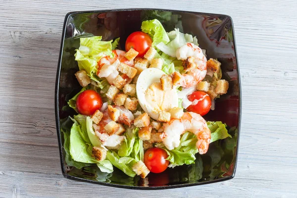 Caesar-Salat mit Garnele auf schwarzem Teller — Stockfoto