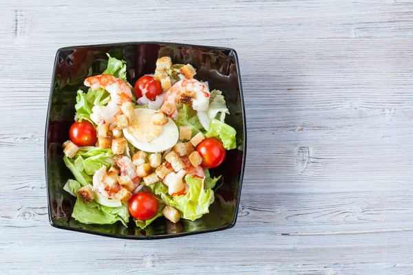 Ansicht von Caesar Salat mit Garnelen in schwarzer Schüssel — Stockfoto