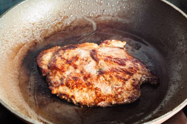 Kızartma tavasında biftek kızartılıyor.