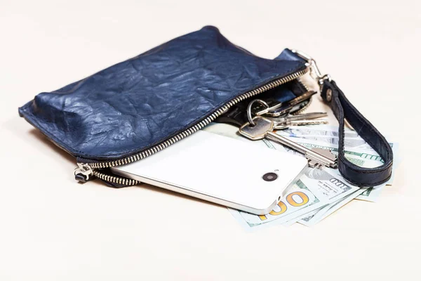 Bolsa com telefone, chaves e dólares americanos na mesa — Fotografia de Stock
