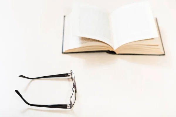 Occhiali e libro aperto su tavolo pallido — Foto Stock