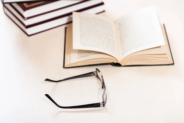 Brille und offenes Buch in der Nähe von Bücherstapeln — Stockfoto