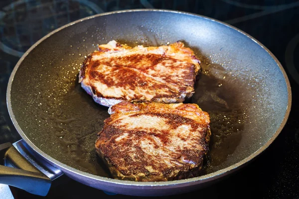 Two fried piece of meat in frying pan on range — Stock Photo, Image