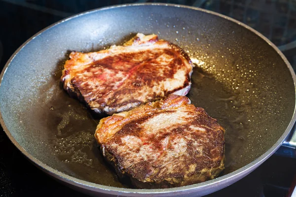 Two roasted piece of meat in frying pan on range — Stock Photo, Image