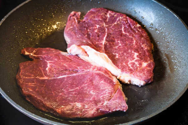 Assar dois bifes de carne na frigideira ao alcance — Fotografia de Stock