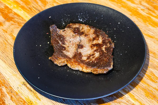 Pedazo de carne asada en plato negro en la mesa — Foto de Stock