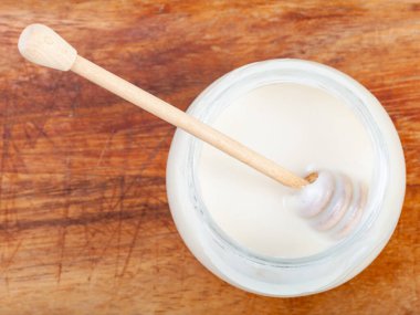 Tahta üzerinde doğal organik beyaz bal bulunan cam kavanozdaki ahşap sopa manzarası