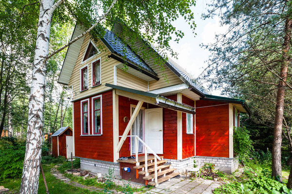 one-storey wooden summerhouse with attic in Russia in summer