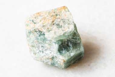 Jeolojik koleksiyondaki doğal mineral örneğinin yakın çekimi - beyaz mermer arka planda ham Apatite kayası