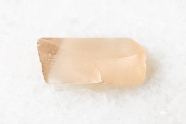 Jeolojik koleksiyondaki doğal mineral örneğinin yakın çekimi - beyaz mermer arka planda cilalanmamış Topaz kristali