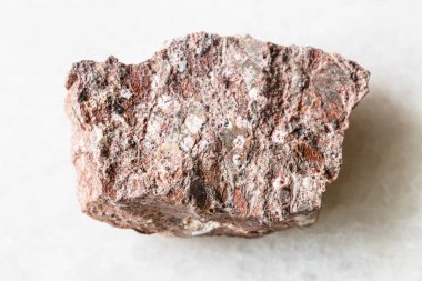 Jeolojik koleksiyondaki doğal mineral örneğinin yakın çekimi - beyaz mermer zemin üzerinde kaba Rhyolite kayası