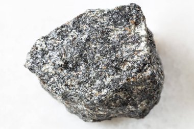 Jeolojik koleksiyondaki doğal mineral örneğinin yakın çekimi - beyaz mermer arka planda kaba Nepheline Syenite kayası