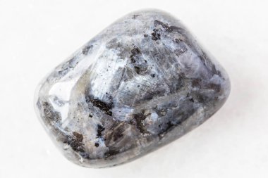 Norveç 'ten gelen beyaz mermer arka planda yuvarlanan Larvikite (Norveç Labradoriti) doğal mineral numunesinin yakın çekimi