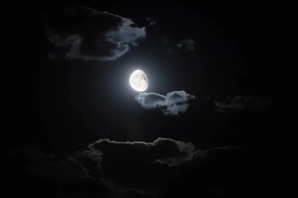 illuminated moon between clouds in black autumn sky in night