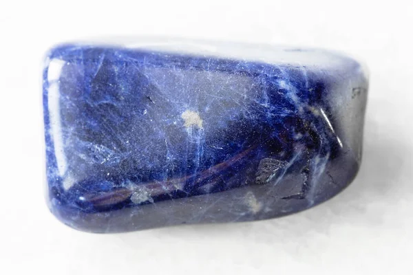 Jeolojik koleksiyondaki doğal mineral örneğinin yakın çekimi - Brezilya 'nın beyaz mermer arka planında cilalanmış Sodalite kayası