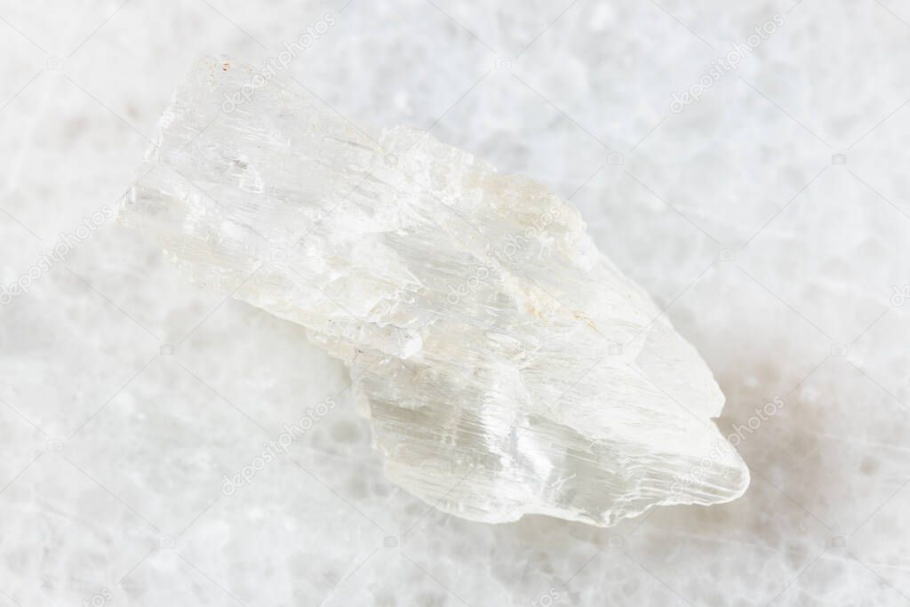 closeup of sample of natural mineral from geological collection - rough Petalite rock on white marble background from Araguai, Brazil