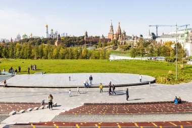 MOSCOW, RUSSIA - SEPTEMBER 27, 2020: Zaryadye kentsel manzara parkındaki Grand Amfitiyatrosunda yürüyen ziyaretçiler ve güneşli Eylül gününde ufuk üzerindeki Kremlin Kuleleri manzarası