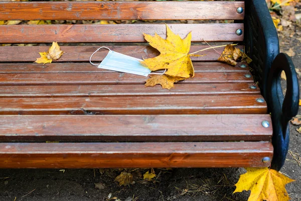 秋天的一天 在城市公园的木制长椅上放了医疗面瓶和黄色枫叶 — 图库照片