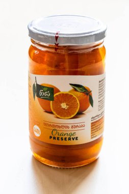 Tbilisi, Georgia - June 17, 2025: glass jar with Georgian preserve made from sliced local oranges on wooden board